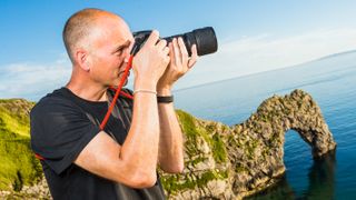 photographer using DSLR camera on coastal path at Durdle Door, Dorset, UK