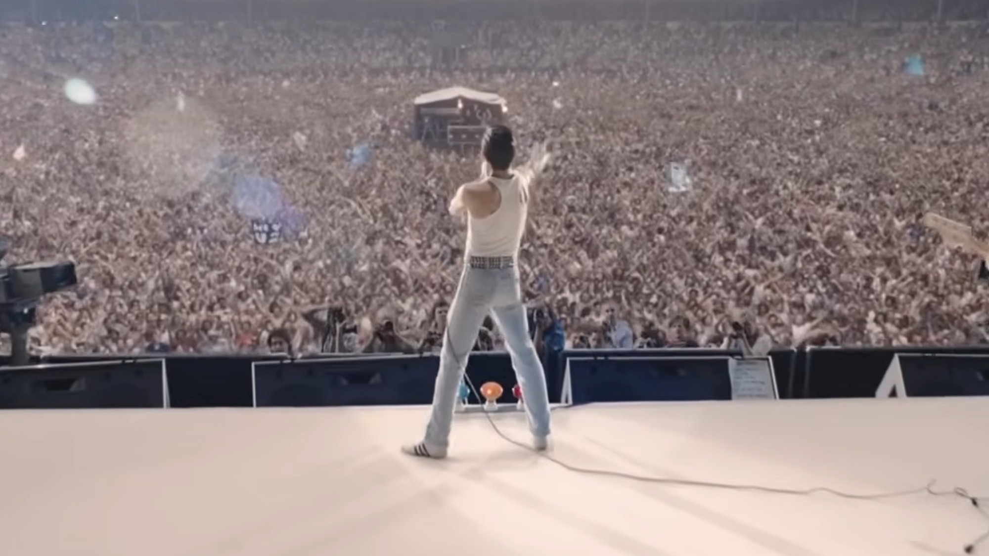 Rami Malek as Freddie Mercury with his back to the camera, facing a huge crowd at Live Aid in Bohemian Rhapsody