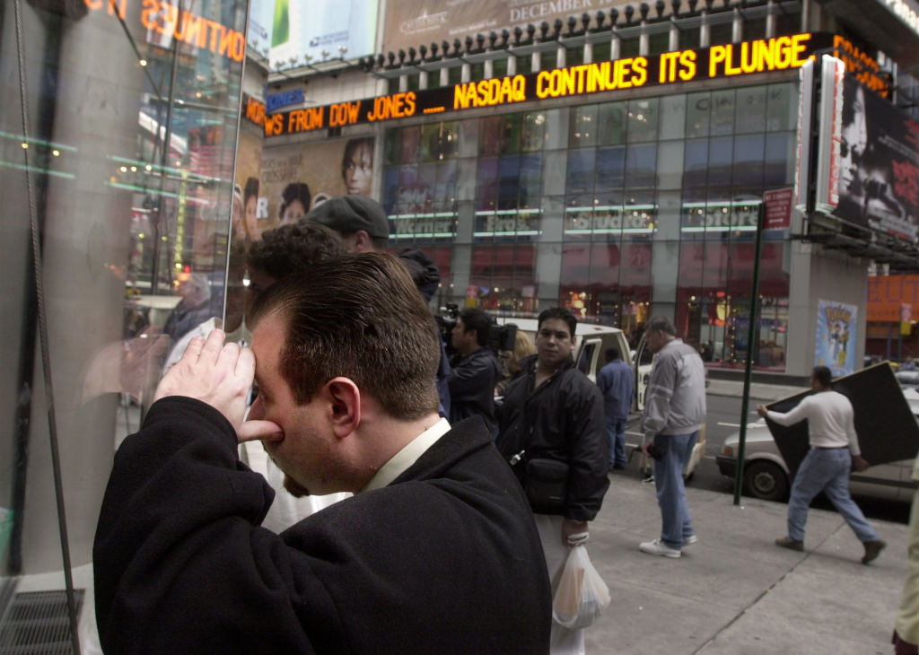 Len Anker, who has money in Nasdaq stocks, peers through a window at the Nasdaq board in Times Square in New York City, N.Y., April 4, 2000
