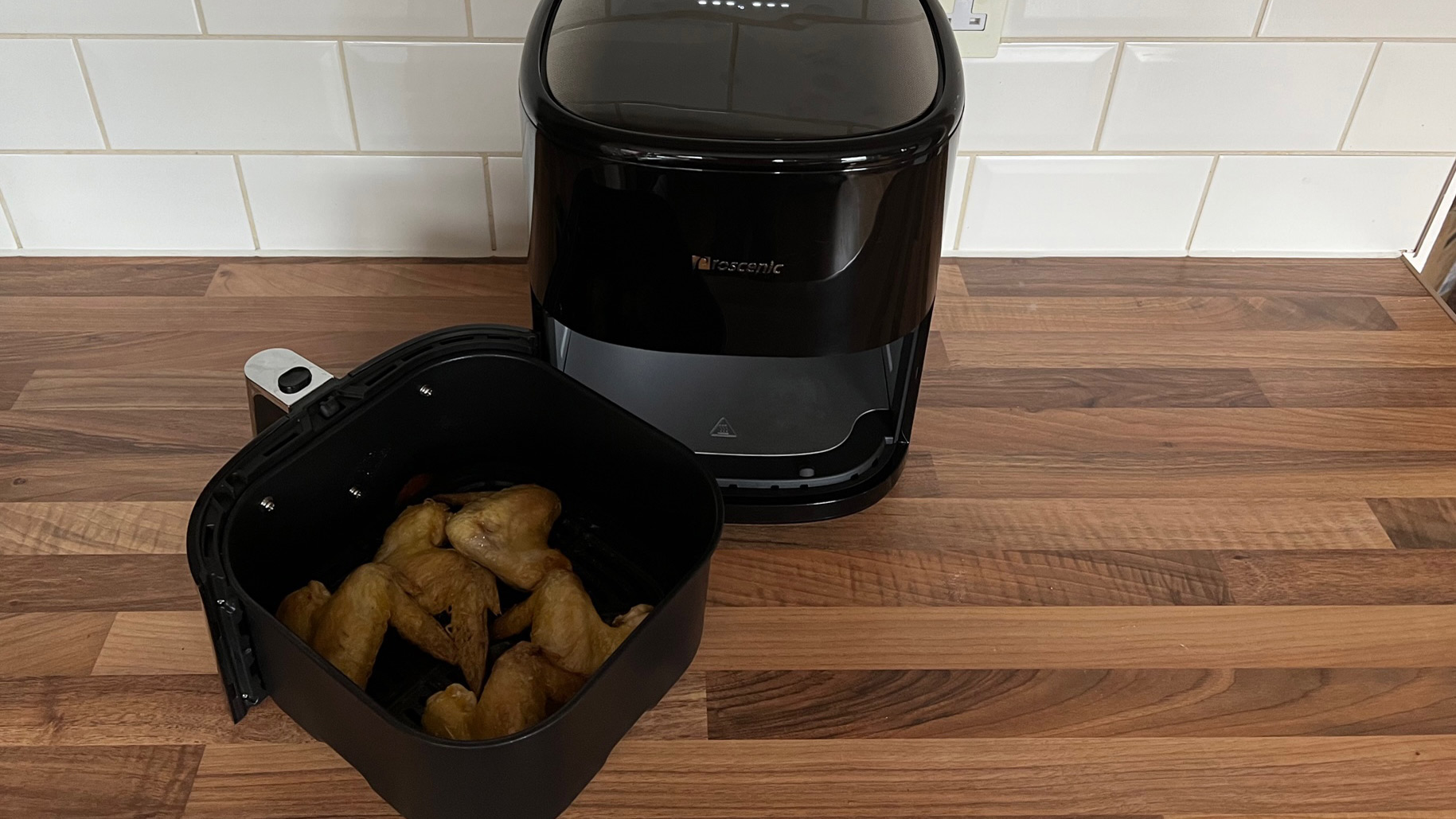 The Proscenic T22 Air Fryer with chicken wings in its frying basket