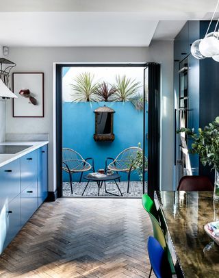 small patio garden at the end of a blue kitchen with blue painted wall