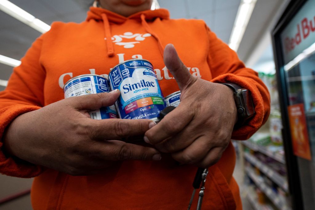 Man holding cans of baby formula.