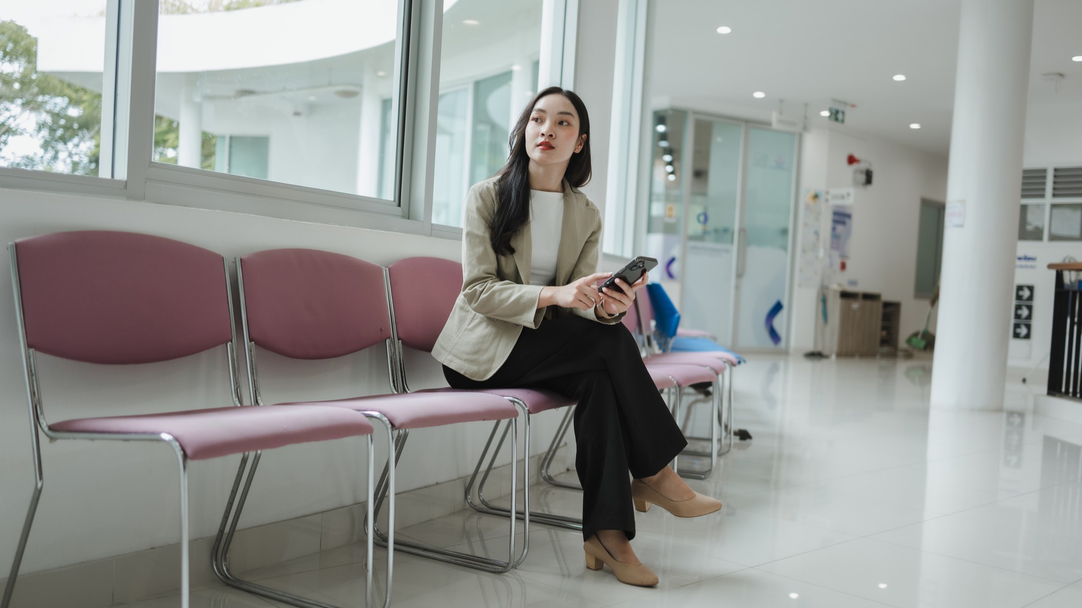 A young woman dressed professionally waits at a medical facility. 