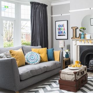 living area with grey sofa and curtain