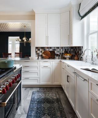 A white kitchen with tiles, blinds, and a rug adding instant warmth