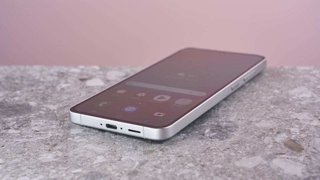 Samsung Galaxy S24 FE on stone surface showing home screen menu