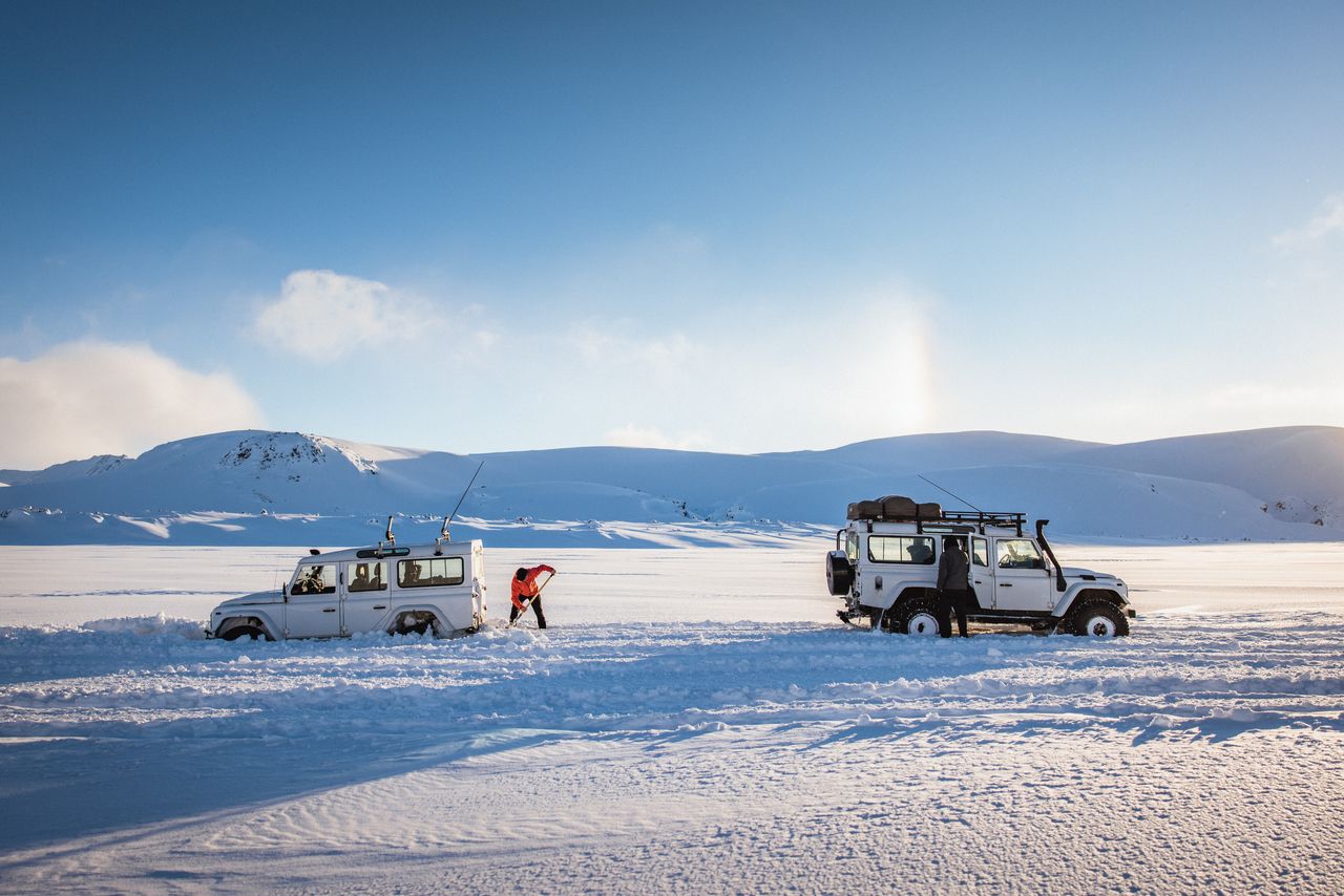 Two white Land Rover Defenders in the snow