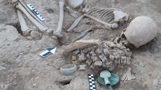 A human skeleton surrounded by artifacts. 