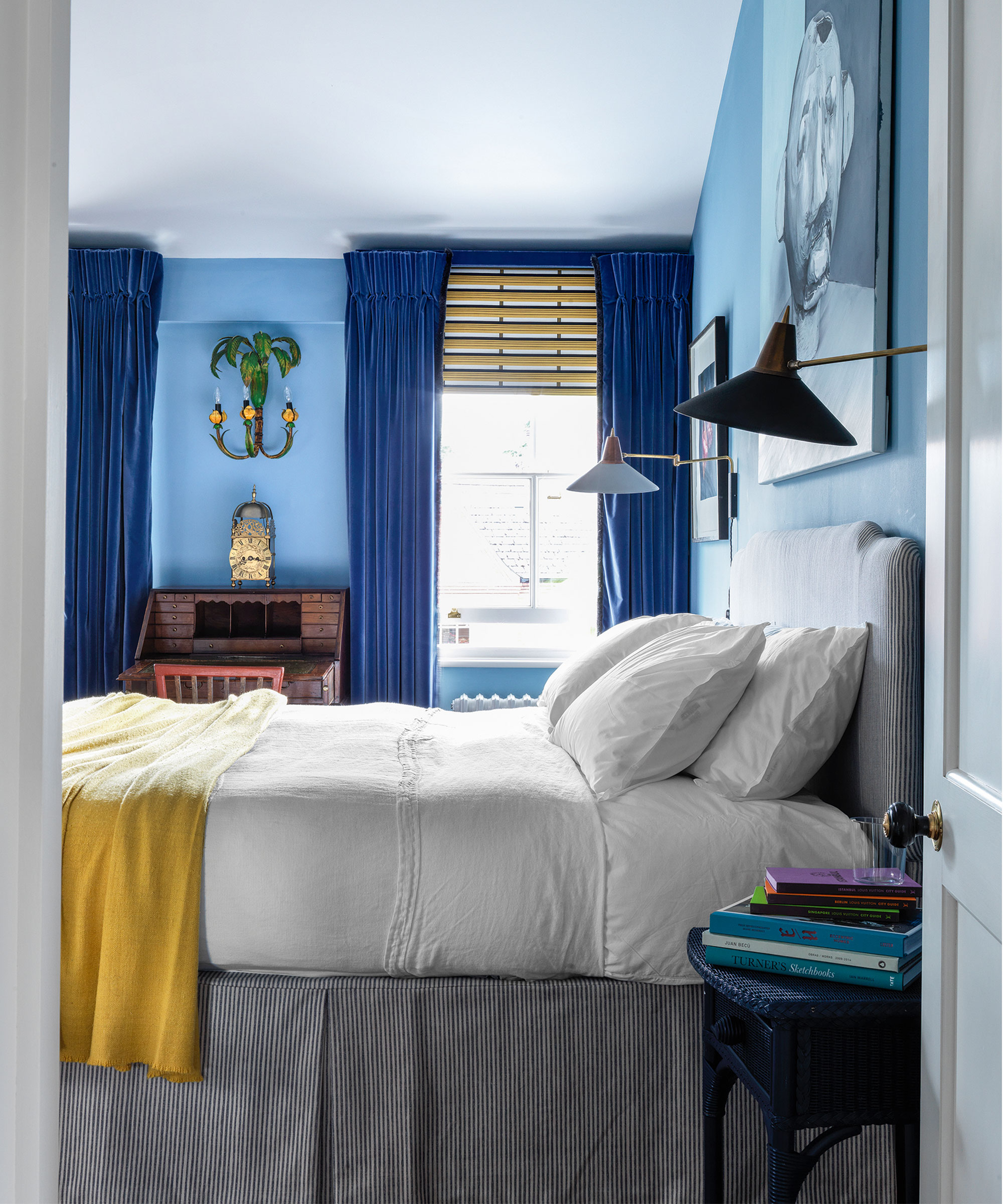 A side view shot of a white bed with a yellow throw under cone shaped wall lights