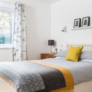 exterior of scandi house guest bedroom with picture ledge and bed linen and bed
