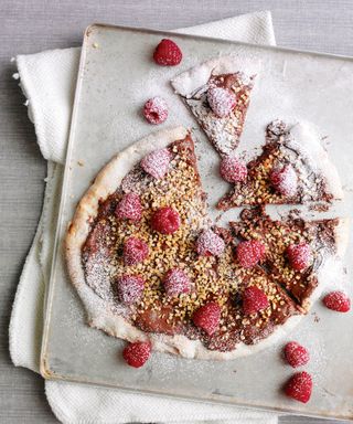 A sweet pizza with raspberries, chocolates and nuts