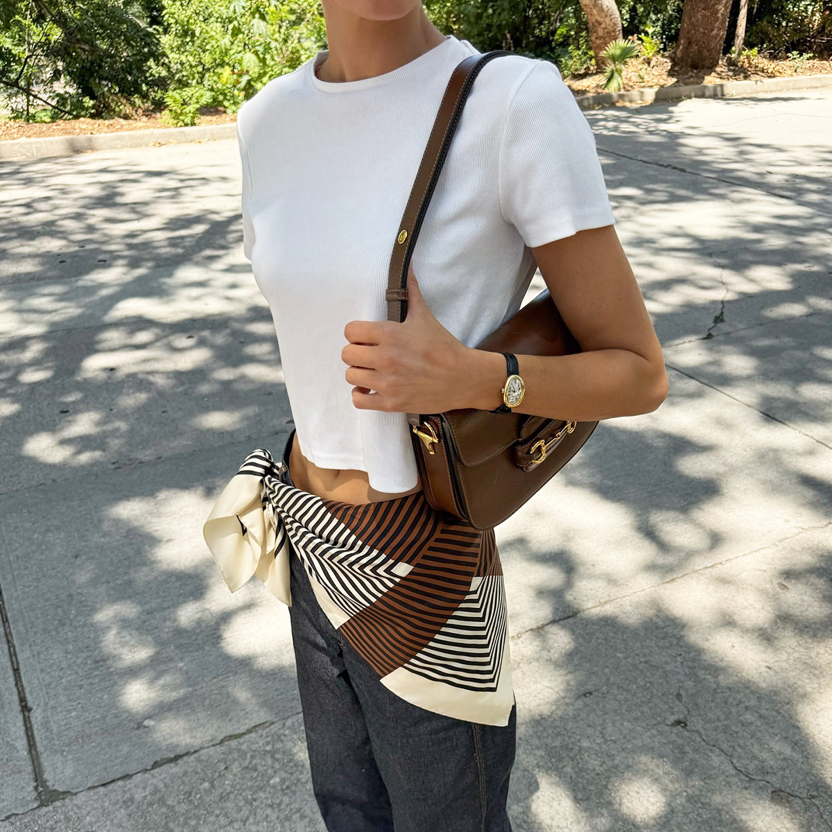 Elsa Hosk wearing a white Helsa T-shirt, Gucci bag, jeans, and scarf belt
