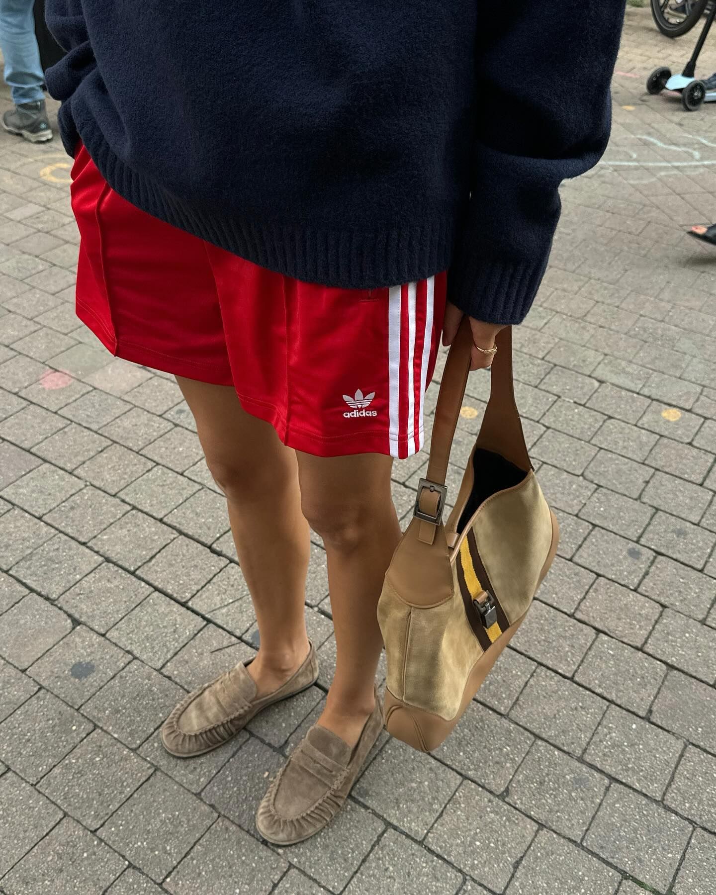 Woman in suede loafers, red shorts, and a navy sweater