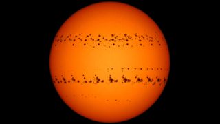 A time-lapse image of the sun showing two bands of sunspots stretched across the sun's surface