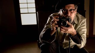 Johnny Depp holding a camera in a shot from Minamata
