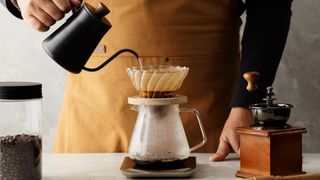 A person pouring water over coffee, representing an article about how to make pour over coffee