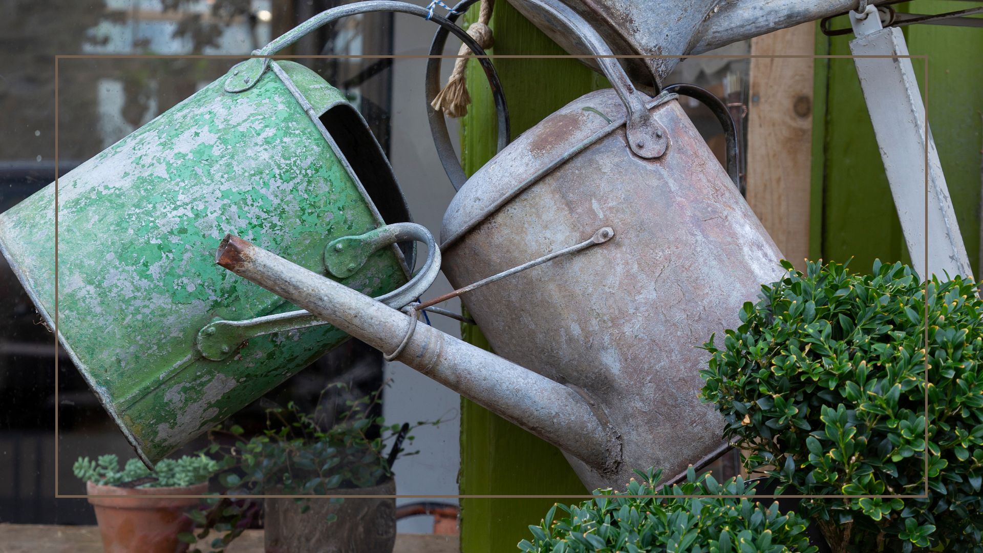 Zinc watering cans hanging on a garden post