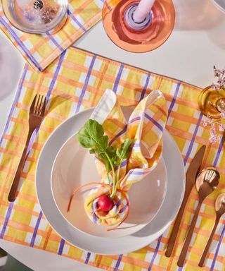 colorful table with gingham tablecloth, napkin and orange candle holder