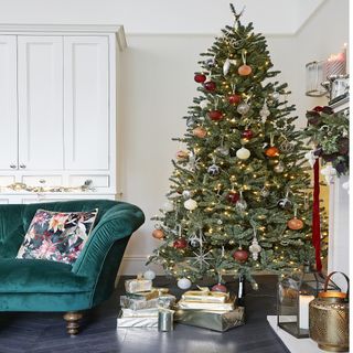 Christmas tree with gold presents underneath next to green sofa