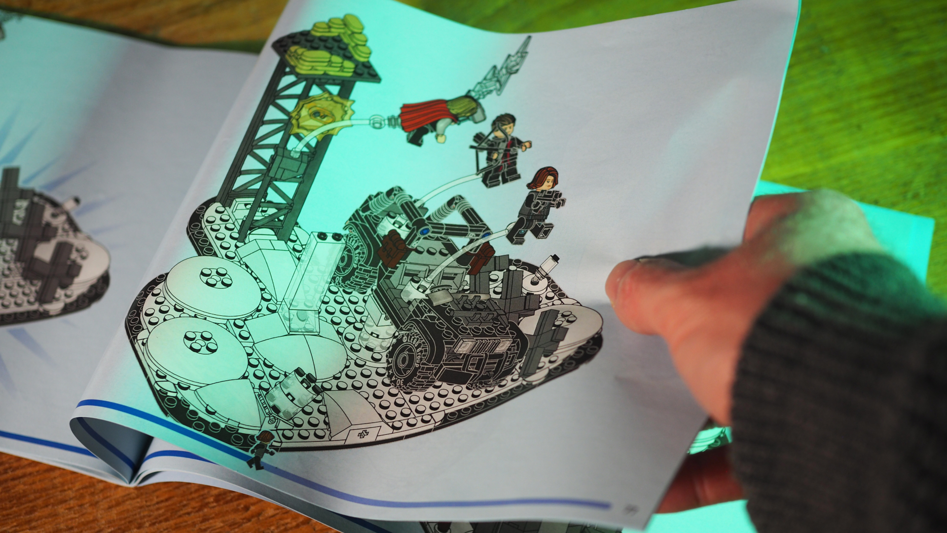 A hand turns the page of the instruction booklet for Lego The Avengers Assemble: Age of Ultron