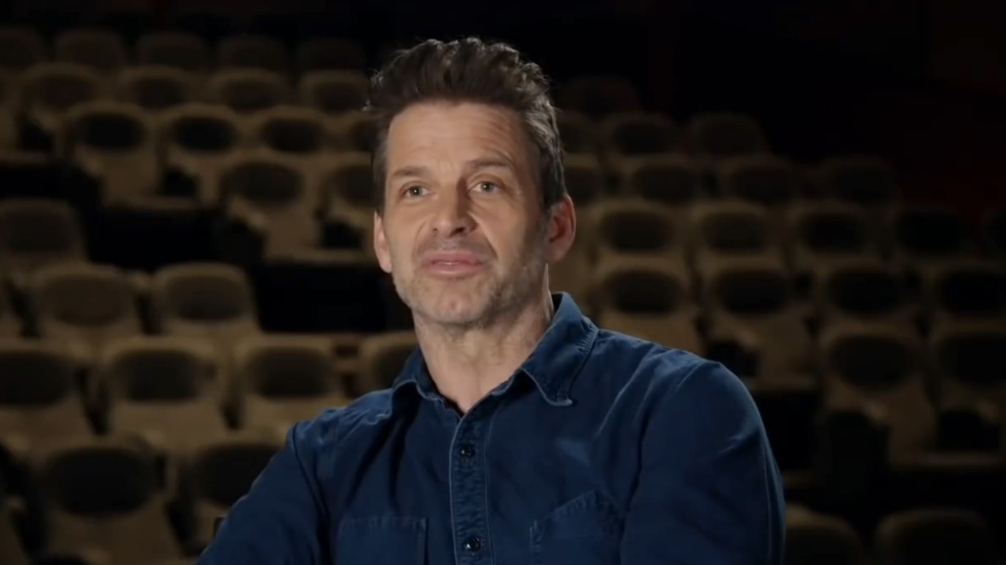 Zack Snyder, dressed in denim button up, sits for an interview discussing the making of his 4 hour vision of the Justice League. 