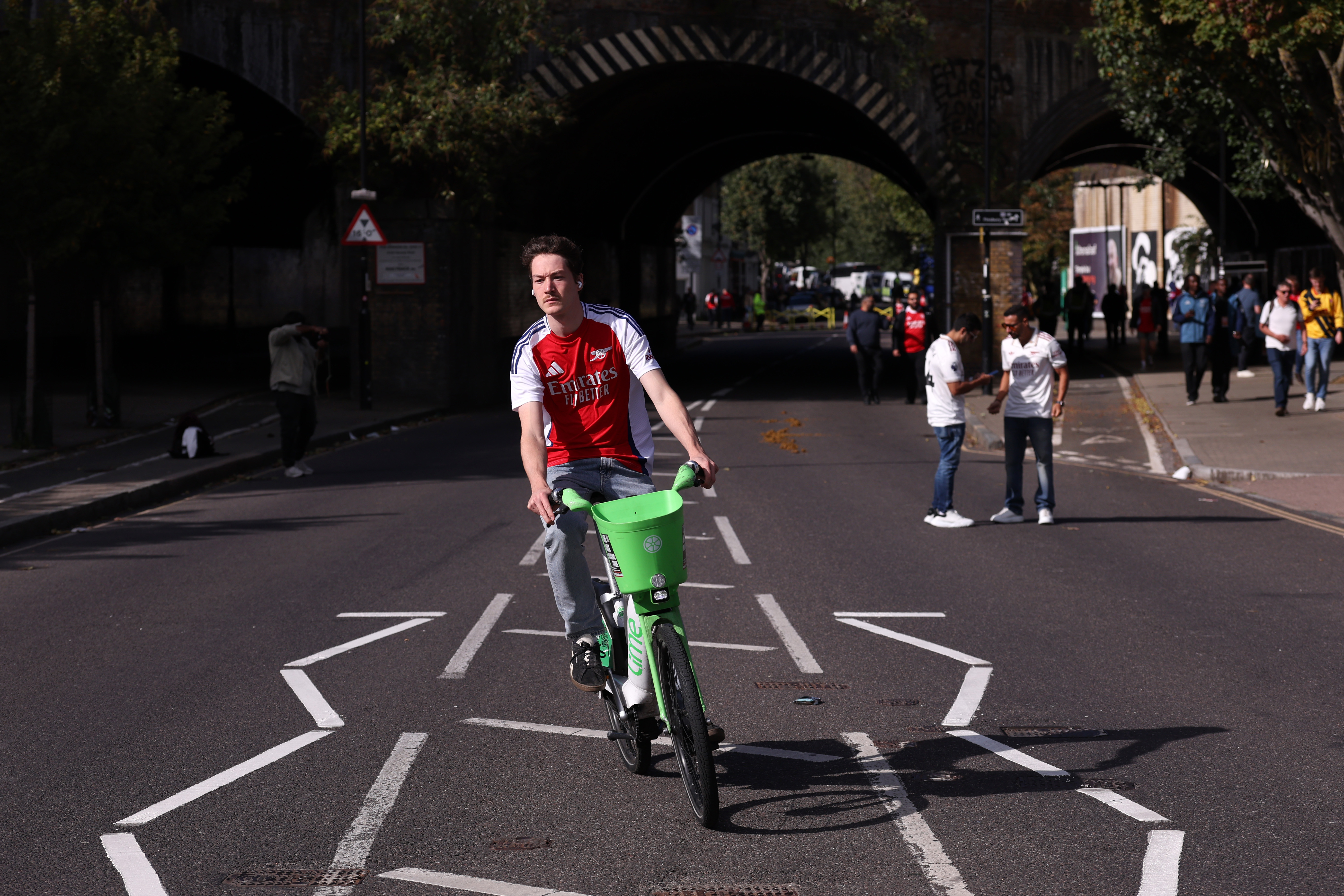 An Arsenal fan on a Lime bike ahead of the Premier League match between Arsenal and Manchester City at Emirates Stadium on September 21, 2025 in London, England. (Photo by Catherine Ivill - AMA/Getty Images)