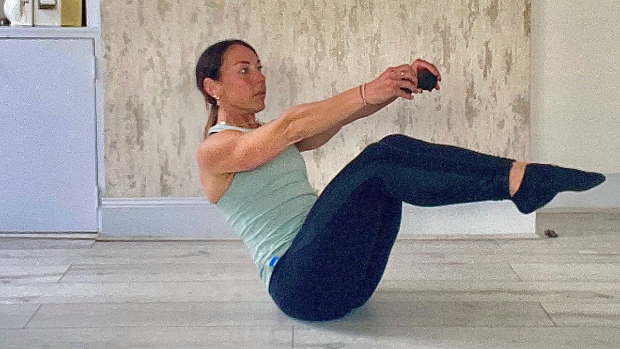 Lucy Miller performing seated Russian twists with dumbbell