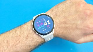 Close-up of the Garmin Forerunner 70 on a user's wrist against a bright blue background