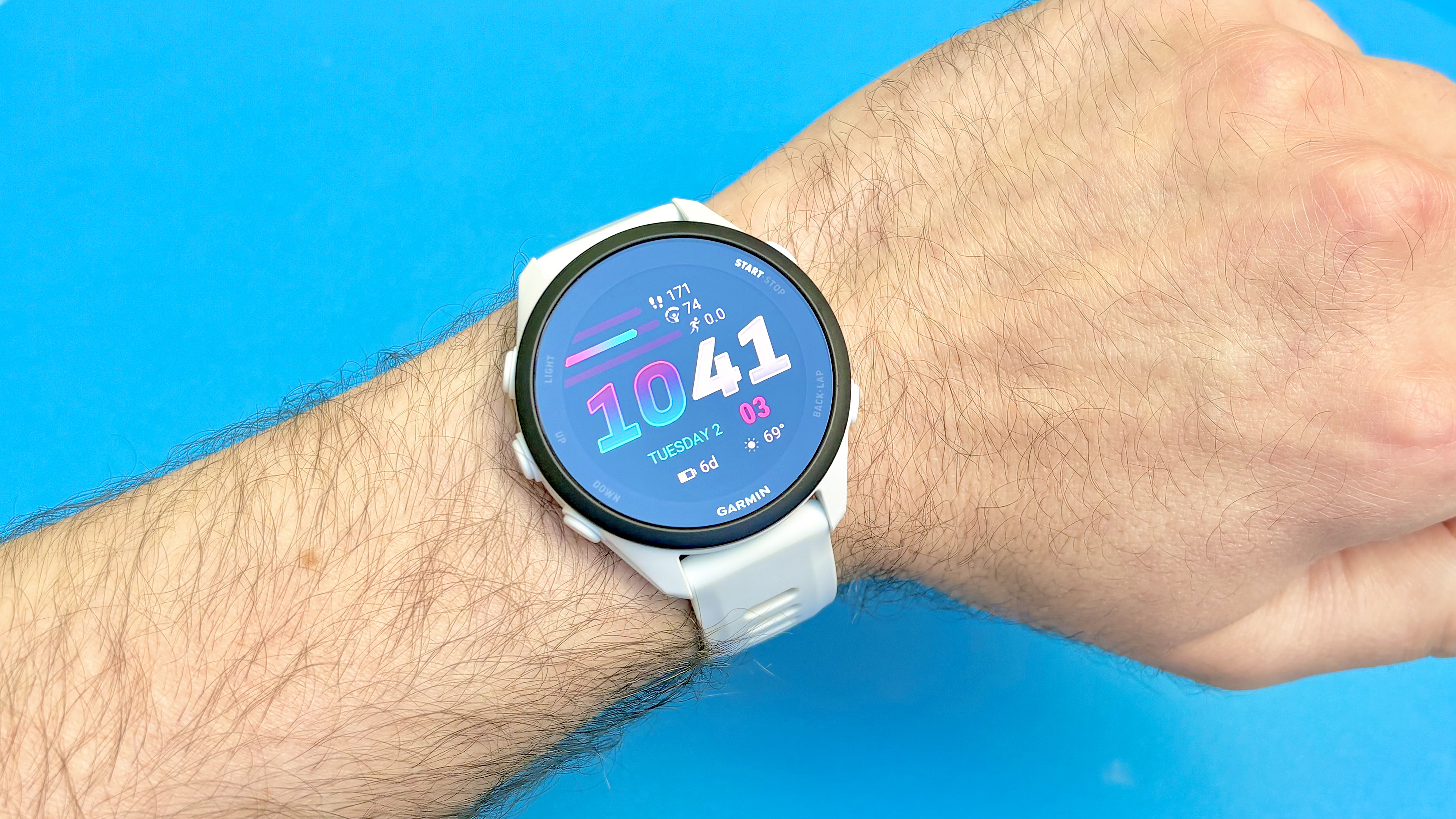Close-up of the Garmin Forerunner 70 on a user's wrist against a bright blue background