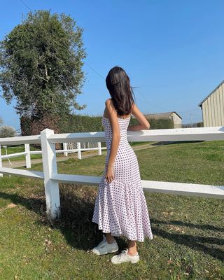 woman wearing white sneakers with polka dot dress spring outfit