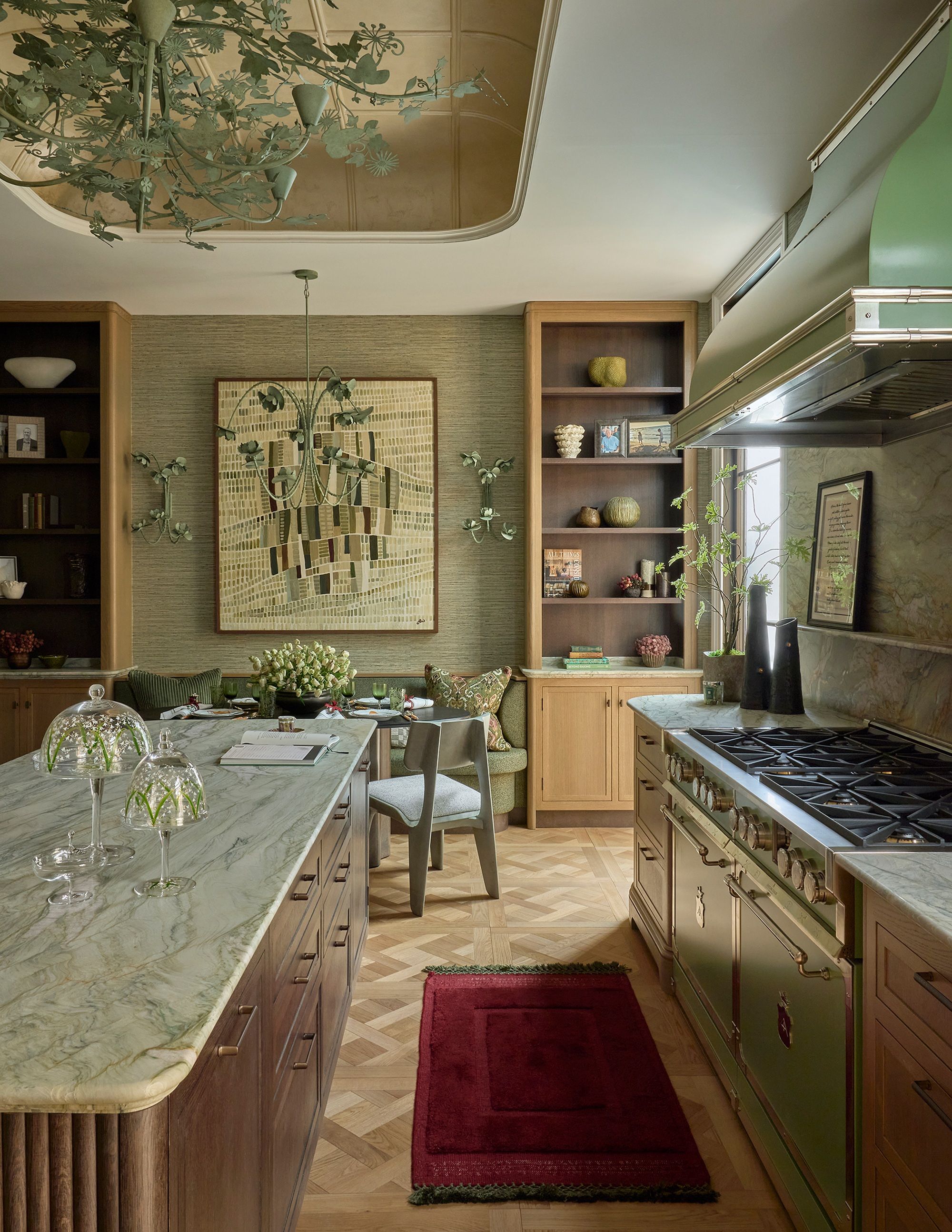a light green kitchen space with a marble and wood island, and a green colored range cooker. 