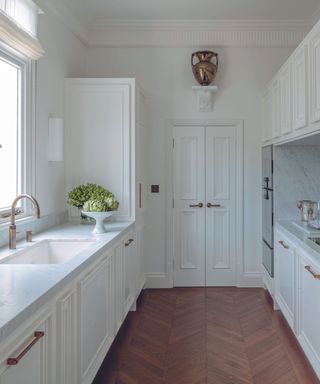 white modern kitchen with wooden floorboards and white walls