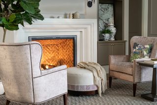 two chairs in front of fireplace with small footstool