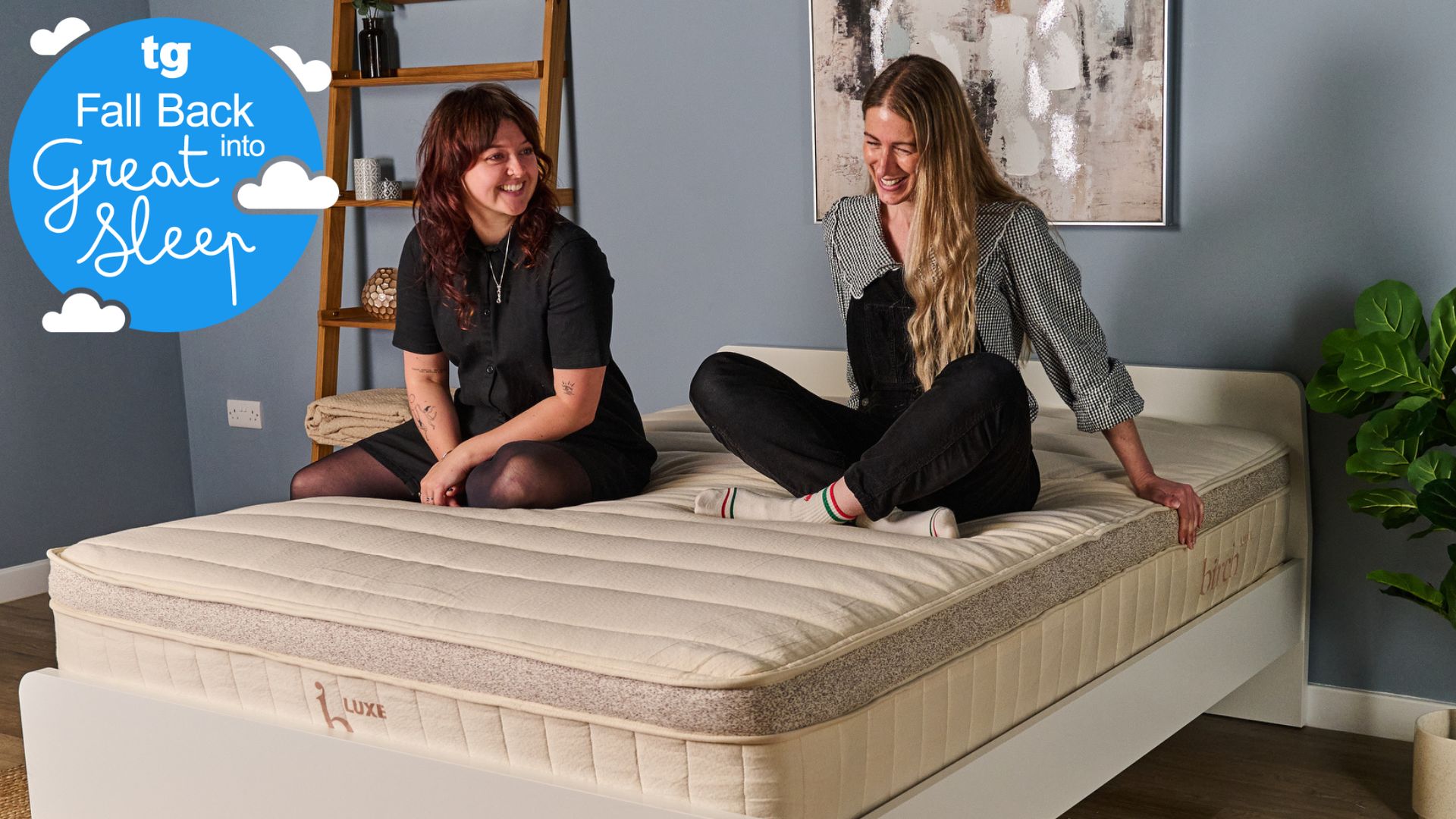 Two Tom&#039;s Guide testers sitting on the Birch Luxe mattress smiling and laughing