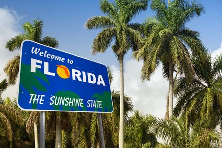 Welcome to Florida sign with palm trees in the background. 