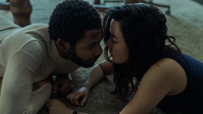 a man (donald glover as john smith) and a woman (maya erskine as jane smith) look at each other while lying on a floor