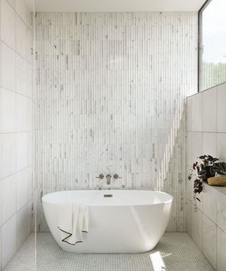 white bathroom with white tub and textural white tiles