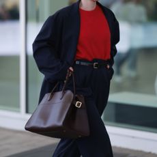 a woman wears The Row's Margaux Bag