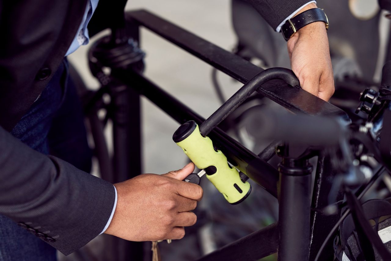 smarty dressed gentleman locking up a hybrid bike with a U-lock