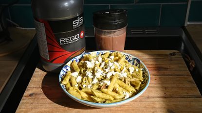 Bowl of pasta and a protein drink on a kitchen surface