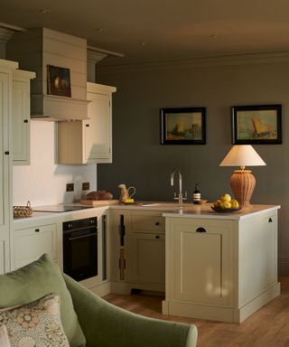 small pale green kitchen with a rattan table lamp and cozy coastal style