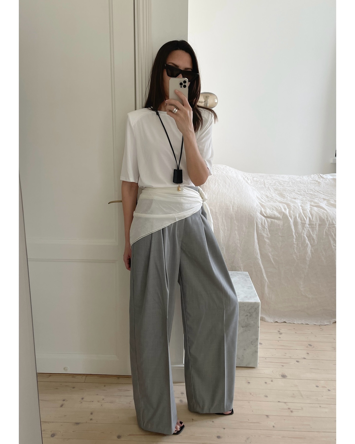 Woman in white t-shirt, gray pants and black pendant necklace