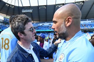 Noel Gallagher speaks to Pep Guardiola after Manchester City's Premier League match against Huddersfield in 2018.