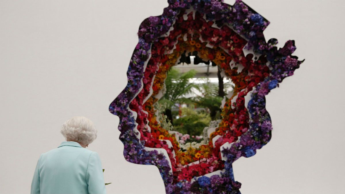 The Queen looks at a floral exhibit featuring an image of her head from the New Covent Garden Flower Market