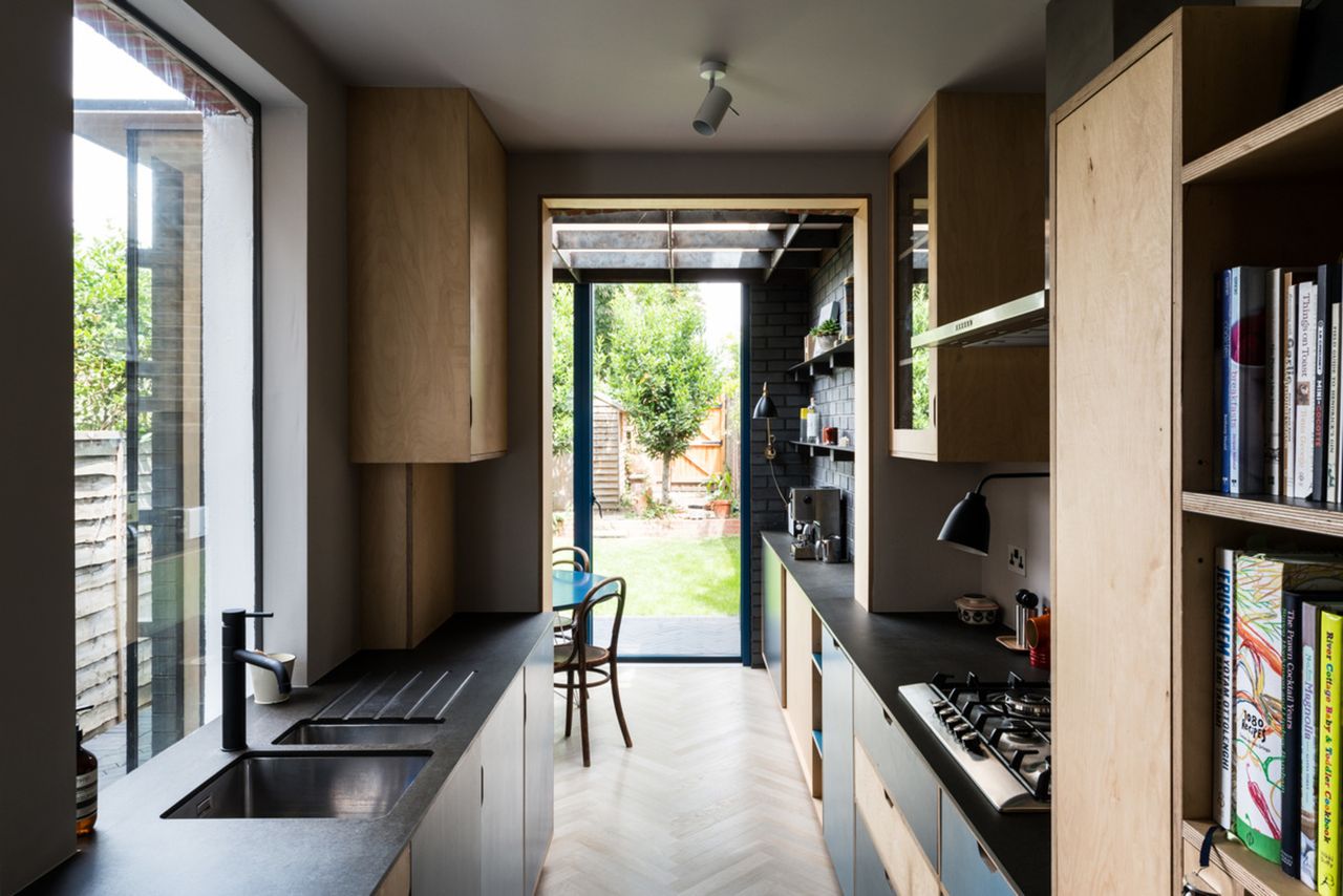 sustainable home with small galley kitchen with black countertops and parquetry floors