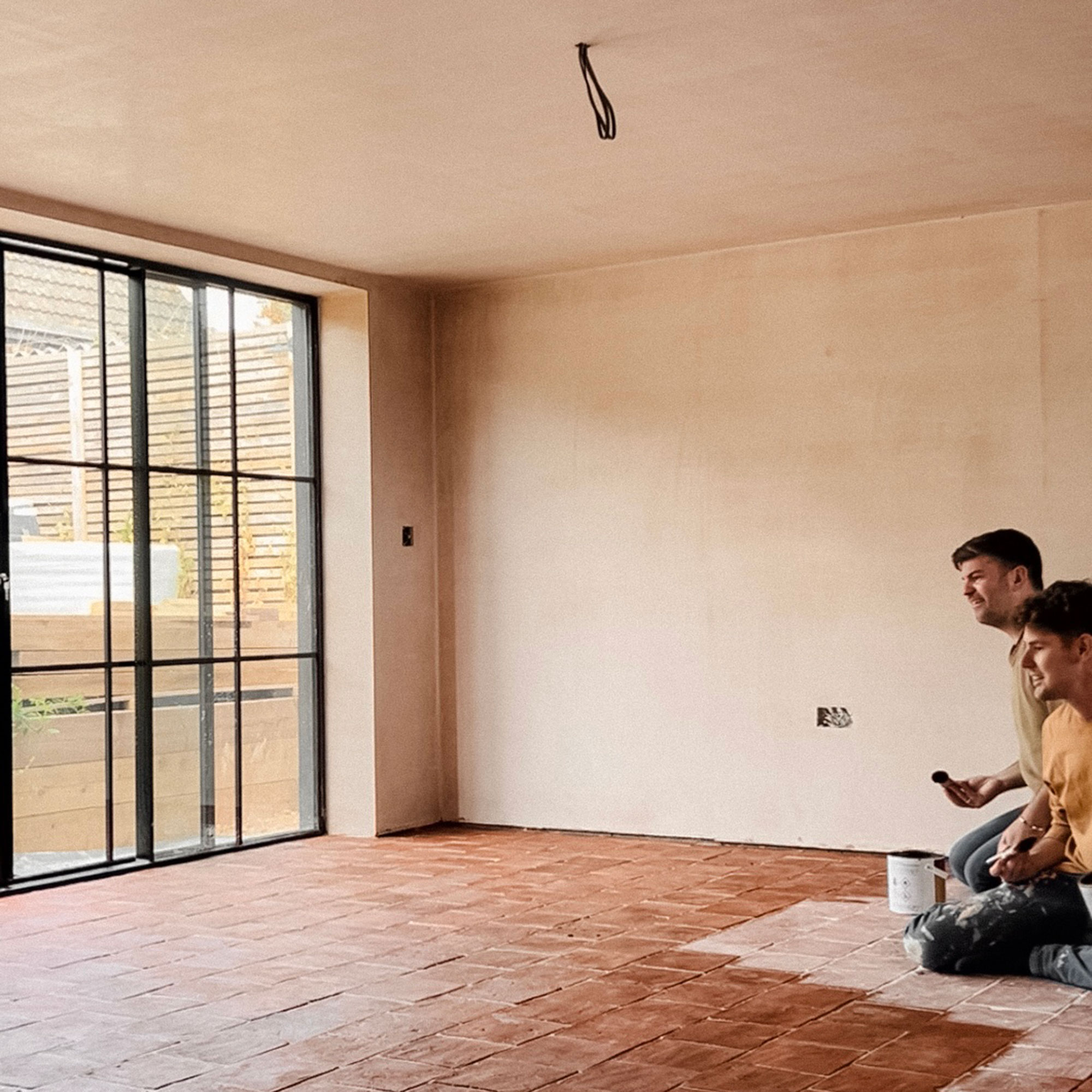Two men kneeling on floor staining tiled floor