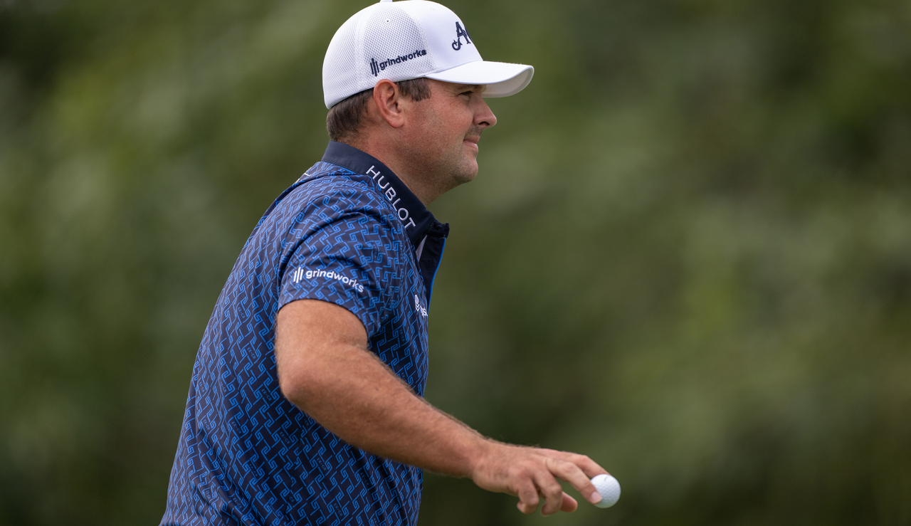 Patrick Reed waves to the crowd after holing a putt