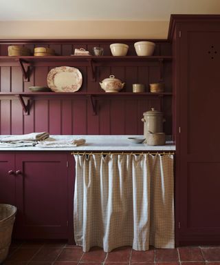 A burgundy kitchen features open shelf cabinetry and a curtain cabinet