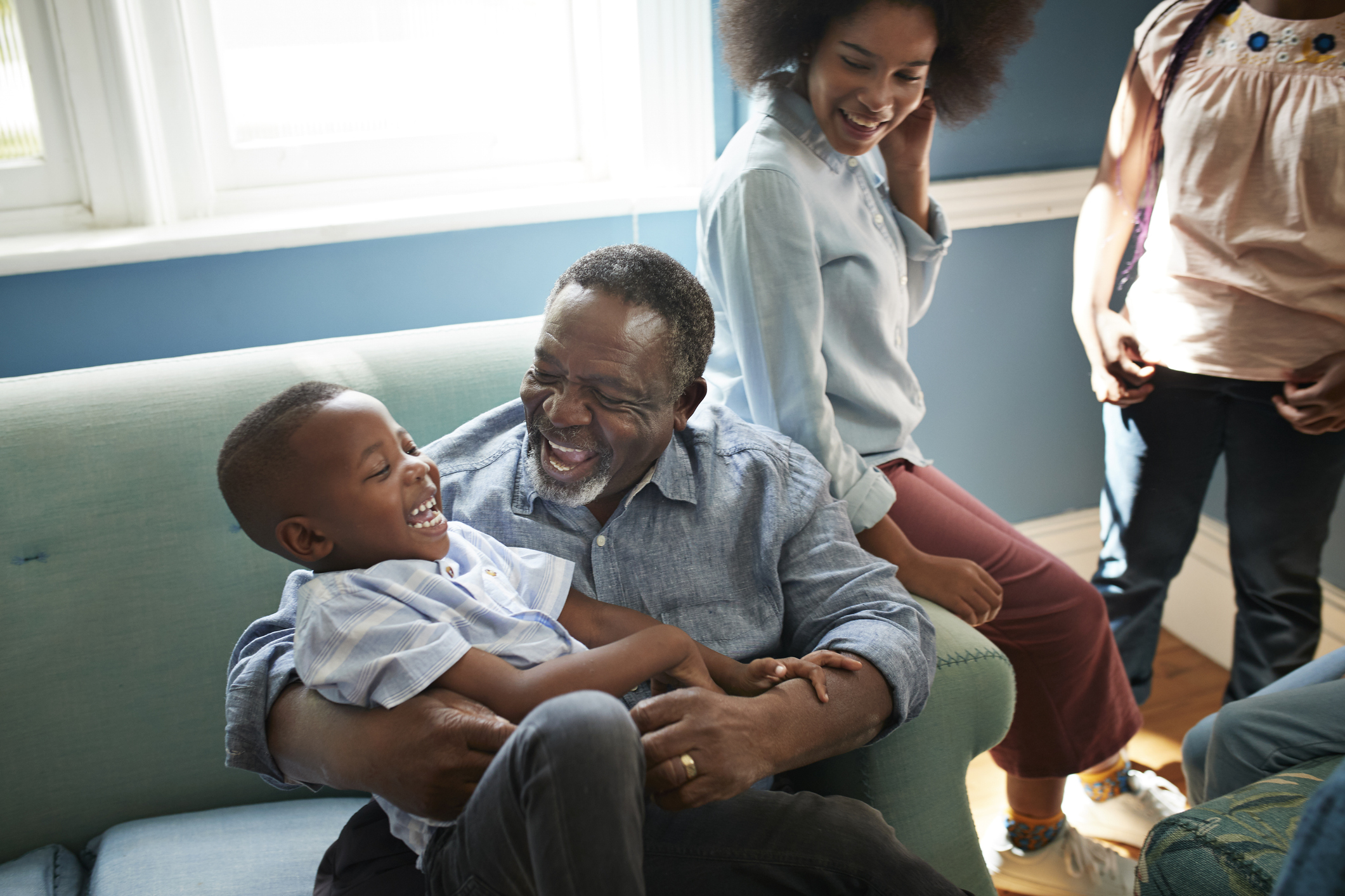High angle view of happy man playing with boy while sitting on sofa at home