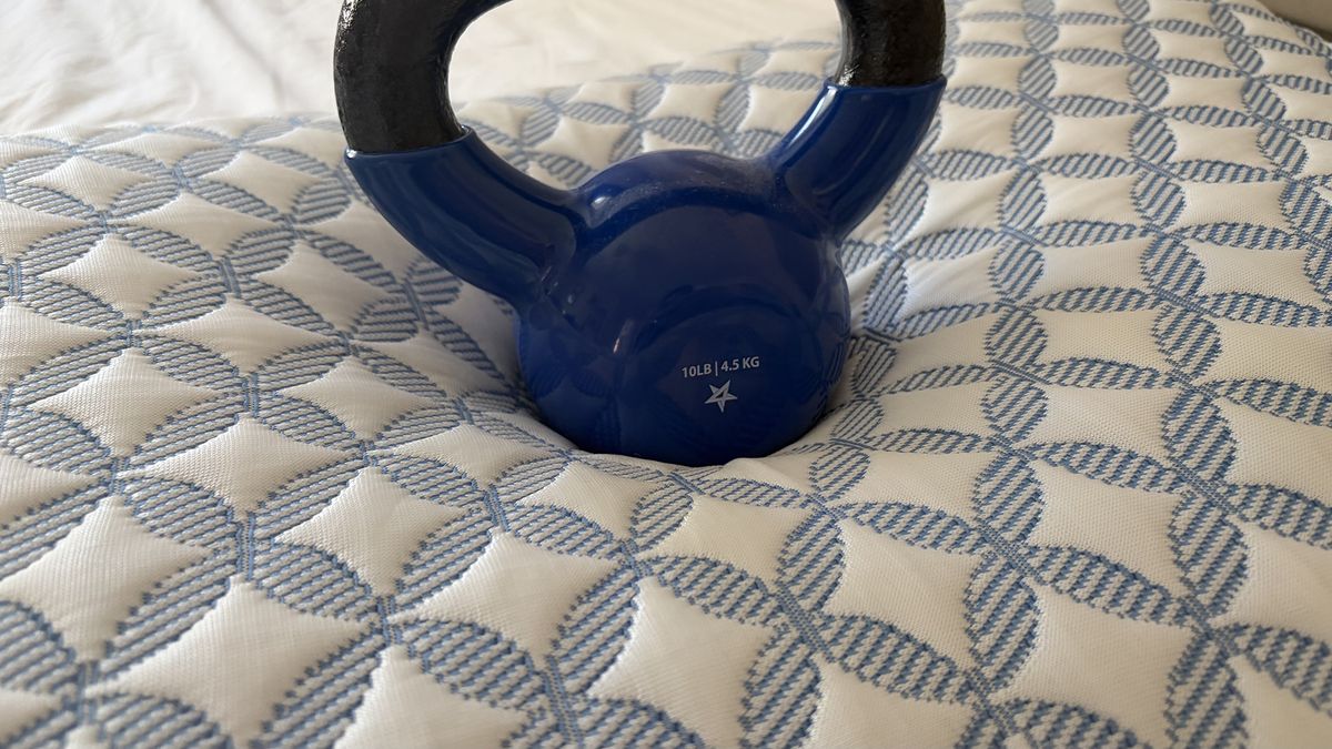 A close up of a 10lb weight on the Helix Cooling Memory Foam pillow in our reviewer's bedroom